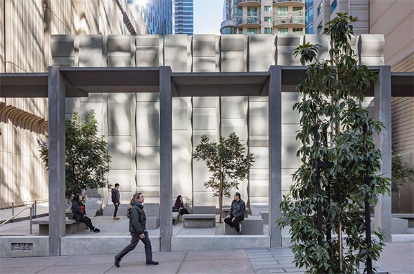 The public plaza at the Embarcadero Substation, with people seated and walking beneath its concrete frame